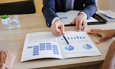 advisor showing financial brochure to clients at desk